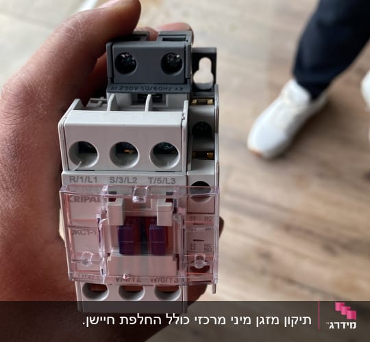 רכיב חשמלי ביד על רקע רצפה